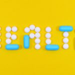 Pills spelling 'health' on a vibrant yellow background, symbolizing wellness.