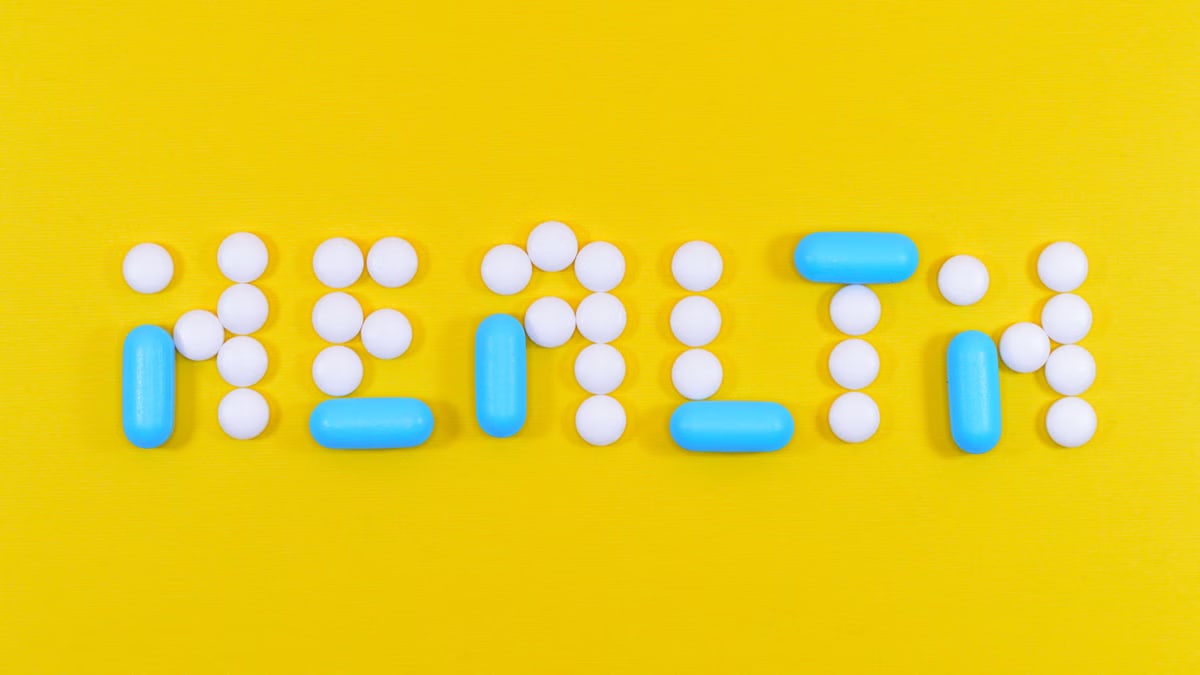 Pills spelling 'health' on a vibrant yellow background, symbolizing wellness.