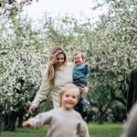 A joyful family enjoys a playful day outdoors amidst blossoming trees in spring.